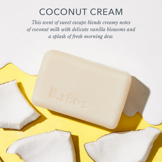 Infographic image of an unwrapped Beekman 1802 Coconut Cream bar soap surrounded by goat milk spill and pieces of coconut, with the words "Coconut Cream. This scent of sweet escape blends creamy notes of coconut milk with delicate vanilla blossoms and a splash of fresh morning dew."