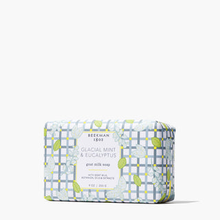 Wrapped bar of Beekman 1802's Glacial Mint & Eucalyptus Goat Milk Soap designed in gingham and leaves, standing on a white background.