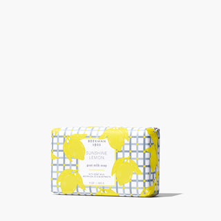 Bar of Beekman 1802's 9oz Sunshine Lemon Bar Soap wrapped in paper covered in yellow lemons on a white background.