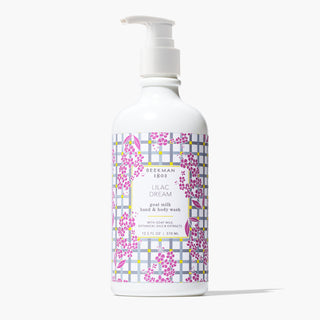white Bottle of Beekman 1802's Lilac Dream Hand & Body Wash with with gingham label designed with lilac flowers and a white nozzle on top, standing on a white background. 