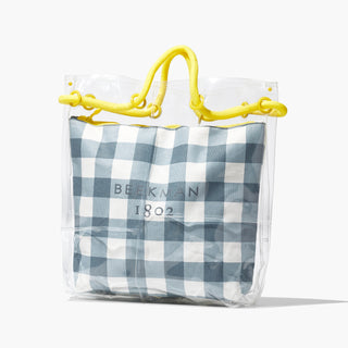 Beekman 1802 Gingham tote bag which is patterned with grey and white gingham and a plastic layer on the outside of the bag, and yellow handles, standing on a light gray background. 