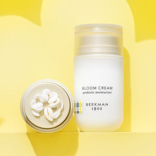 One pack of Bloom Cream standing and one laying down showing bloom cream goop on yellow background as a flower