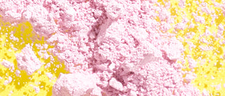 Image of pink Calamine ingredient in powder form spread across a yellow background. 