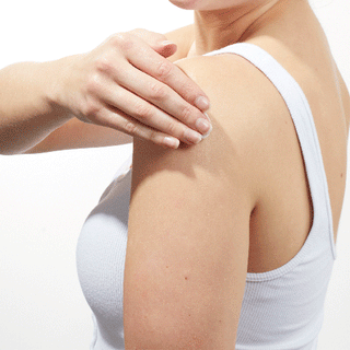 GIF of Models shoulder while wearing a white tank top and applying Beekman 1802's Lilac Dream Whipped Body Cream to her arm and rubbing it down. 