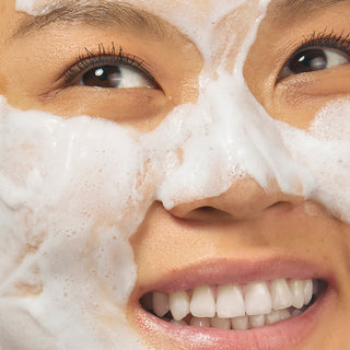 model smiling with foamy goop for exfoliation