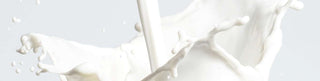 Goat milk being poured, resulting in ripples and splashes against a white background