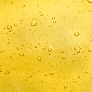 Up close shot of vitamin E ingredient in yellow liquid form with tiny bubbles in the substance.