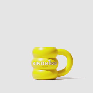 GIF image of Beekman 1802's Yellow Sunshine Ceramic Doughnut Mug spinning 360 degrees, which has the word "Kindness" in white block letters and a goatie on the front of the mug, on a white background