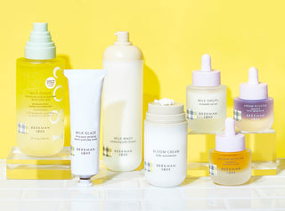Beekman 1802's Clinically Kind line with products on acrylic risers on a yellow background 