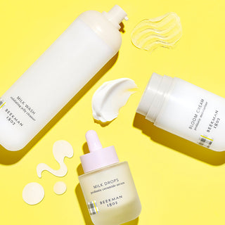 Three products against a yellow background: Milk Wash, Milk Drops, and Bloom Cream 