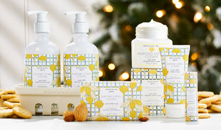 Collection shot of Beekman 1802's Almond honey Cookie bodycare products surrounded by cookies and a christmas tree in the background.