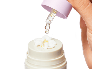 An image of the Collagen Booster serum being dropped into a bloomed Bloom Cream with the serum and moisturizer mixed together on top of the Bloom Cream bottle.