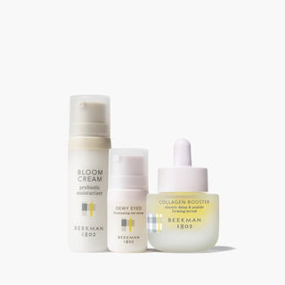 Beekman 1802's Tighten Up Skincare Set which includes a mini bloom cream daily moisturizer, a mini dewy eyed eye serum, and a full size collagen booster, shown lined up next to each other on a white background.
