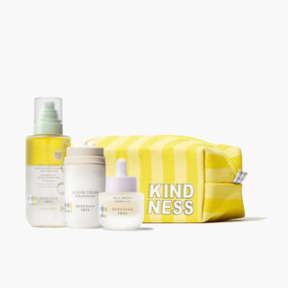 Beekman 1802's Oily Skin starter set which includes the Milk shake toner mist, bloom cream daily moisturizer, and mini milk drops serum and are all lined up in front of a yellow striped dopp bag, on a white background.
