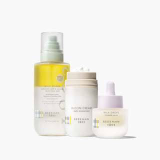 Beekman 1802's Oily Skin starter set which includes the Milk shake toner mist, bloom cream daily moisturizer, and mini milk drops serum, which are all lined up next to each other next to their shadow on a white background.
