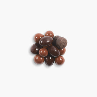 Pile of assorted chocolates from Beekman 1802s's Goat Poop Ultra Premium Chocolates, on a light grey background.