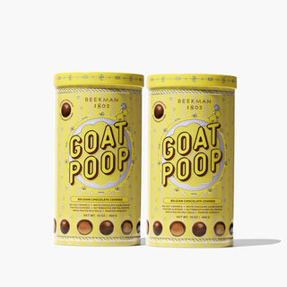 Two Yellow tin of Beekman 1802's 2023 Goat Poop Ultra Premium Chocolates which says "goat poop" on the front while standing next to each other and images of chocolate pieces, on a white background.