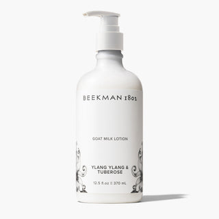 White bottle of Beekman 1802's Ylang Ylang & Tuberose Goat Milk Lotion with white nozzle standing on a white background. 
