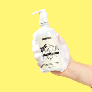 Sudsy Hand holding a white bottle of Beekman 1802's Pure Hand & Body Wash on a yellow background.