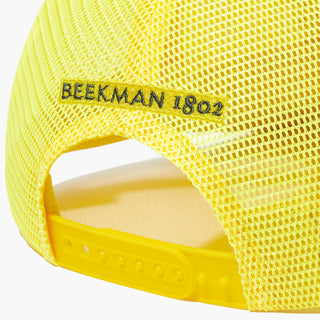 Up close detail shot of the back of the Beekman 1802's Kindness Trucker Hat, which is all yellow with the words "Beekman 1802" in black above the snap adjustment piece.