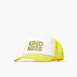 Image of the front of the Beekman 1802's Kindness Trucker Hat, which is colored yellow and white with the word "kindness" on the front of the hat in yellow letters, on a white background.