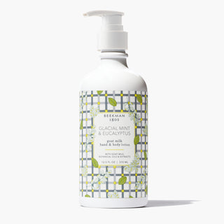 Bottle of Beekman 1802's Glacial Mint & Eucalyptus Goat Milk Lotion, designed with gingham and leaves, standing on a white background. 