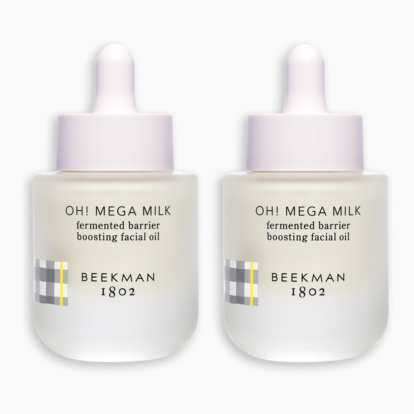 2 bottles of Beekman 1802's Oh! Mega Milk Fermented Barrier Boosting Facial Oil laying next to each other on a white background.