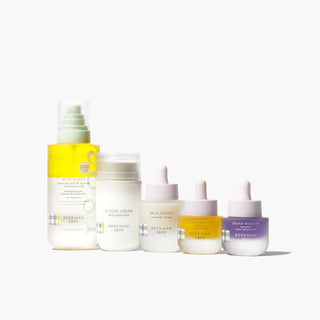 Beekman 1802's Best of the Batch Skincare Bestsellers Set, which shows the Milk Shake toner mist, bloom cream moisturizer, milk drops, golden booster and dream booster serum all lined up next to each other, on a white background.