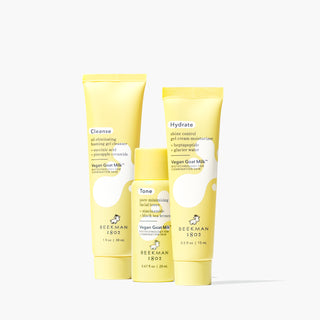 Yellow tubes of Beekman 1802's Vegan Goat Oil Eliminating Foaming Gel Cleanser, Pore Minimizing Facial Toner, and Shine Control Gel Cream Moisturizer, all lined up and standing next to each other on a white background. 