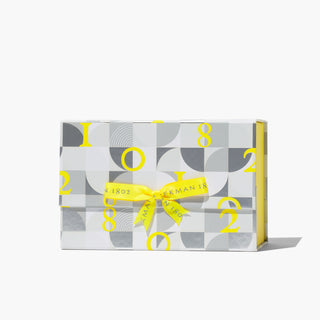 Beekman 1802's Yellow and gray 2022 gift box for holiday with a yellow bow, standing on a white background.