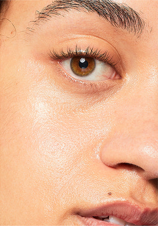 Up close shot of side of models face while looking into the camera, with lips half opened and showing bright skin. 