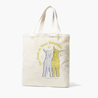Beekman 1802's seasonal fragrance tote for 2024 which is a beige tote with and yellow goat and white goat on the front and words saying "be kind to your neighbor," standing on a white background.
