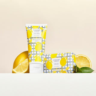 Sunshine lemon 2 oz hand cream and 3.5 oz bar soap in front of sliced lemons.