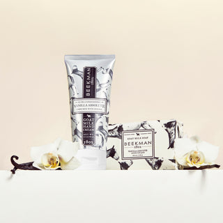 Vanilla Absolute 2 oz hand cream and 3.5 oz bar soap surrounded by vanilla beans and white flowers.