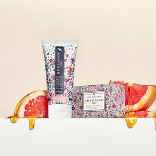Honeyed grapefruit 3.5 oz bar soap and 2 oz hand cream surrounded by sliced grapefruits with honey dripping from them.