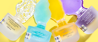 4 Bottles of Beekman 1802's Booster Serums which includes Collagen, Smooth, Golden, and Dream, all tipped over and with product spilling out on yellow background. 