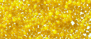 Up close shot of tiny yellow jojoba beads orbs all bunched together. 