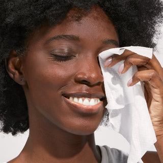 A woman wiping her face with a face wipe.