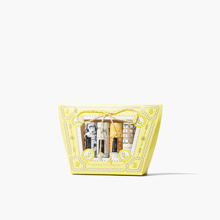 Beekman 1802's Under the Mistletoe 4-Piece Lip Balm Set, which comes with 4 goat milk lip balms in a yellow gift box decorated in a candy design, on a white background.