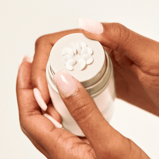 Hand holding and pumping the bloom cream moisturizer.