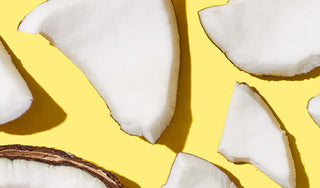 Up close shot of broken up coconut pieces on a yellow background. 
