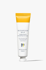 White tube of Beekman 1802's Mushroom Milk Better Aging Eye Cream that is yellow on the sealed end of the tube, standing on a white background.