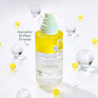 Beekman 1802 Full Size Milk Shake Toner Mist surrounded by clear and yellow spheres with the words "innovative Bi-Phase Formula" next to the bottle. 
