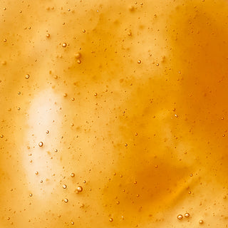 Up close shot of orange potato pulp ingredient in liquid form, with tiny bubbles formed in the substance. 