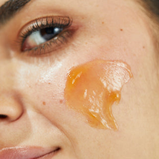 Up close shot of models cheek with Beekman 1802's Potato Peel Rapid Resurfacing Milk Facial smeared on their face, while looking off to the side