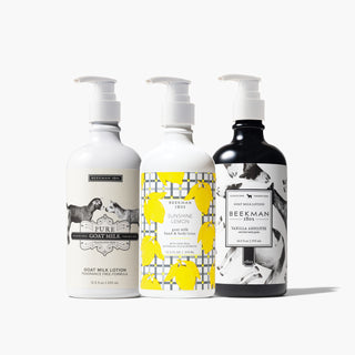 Bottles of Beekman 1802's Pure, sunshine Lemon and vanilla absolute goat milk lotions all lined up next to each other in that order, standing on a light grey background. 