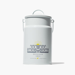 Grey Milk Pail Tin which has the words "Beekman 1802" across the front under an image of the beekman 1802 mansion on the farm, on a light gray backgrouund. 