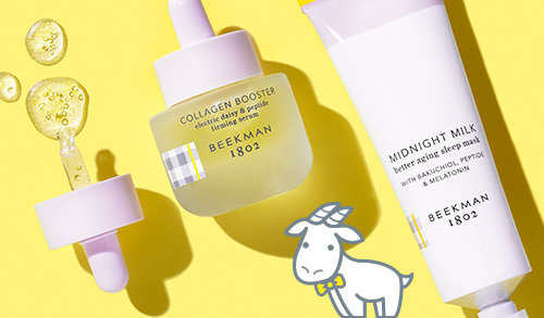 Bottle of Beekman 1802's Collagen Booster Electric Daisy & Peptide Firming Serum and tube of Beekman 1802's Midnight Milk Better Aging Sleep mask on a yellow background, with booster dropper to the left of the products, and serum droplets spilling out of dropper, next to a white cartoon goatie. 