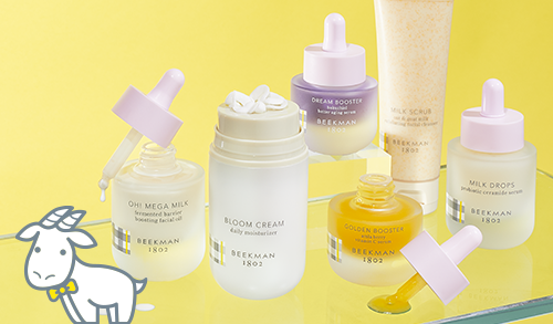 Bottles of Beekman 1802's Clinically Kind Skincare on a yellow background, with white cartoon goatie standing next to one of the bottles. 