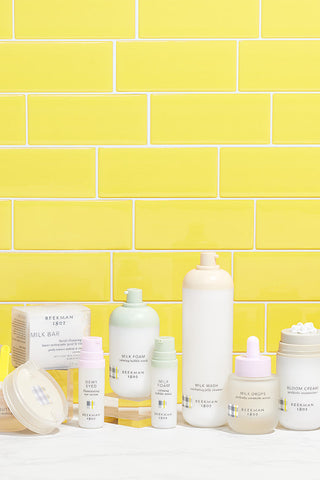 Beekman 1802's collection of Clinically Kind skincare set against a yellow tiled background